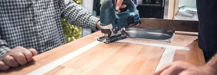 Person sägt Holzplatte mit Stichsäge zu